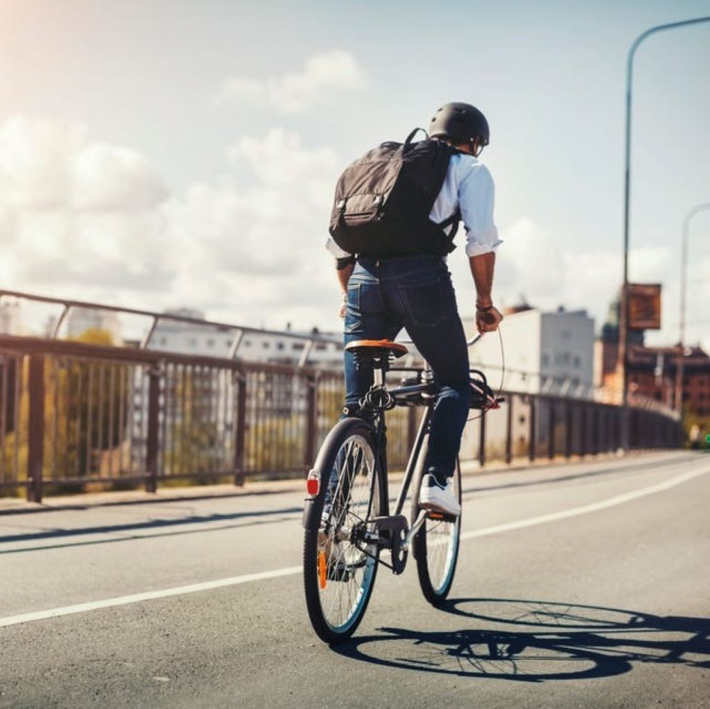 Person commuting to work by bicycle on a city street during sunrise, promoting eco-friendly and healthy transportation
