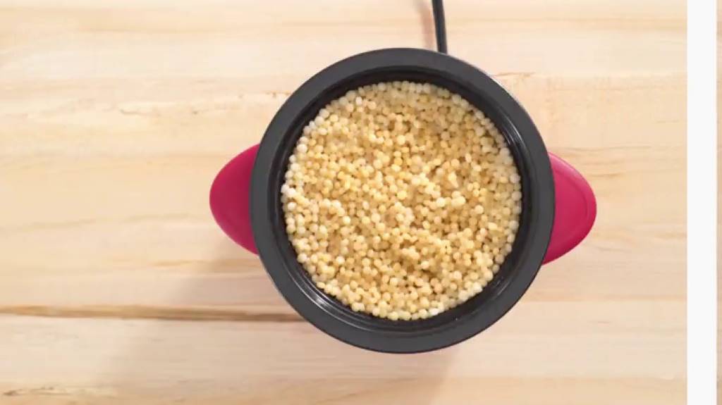 Compact pink Dash Mini Rice Cooker on a kitchen counter with rice paddle