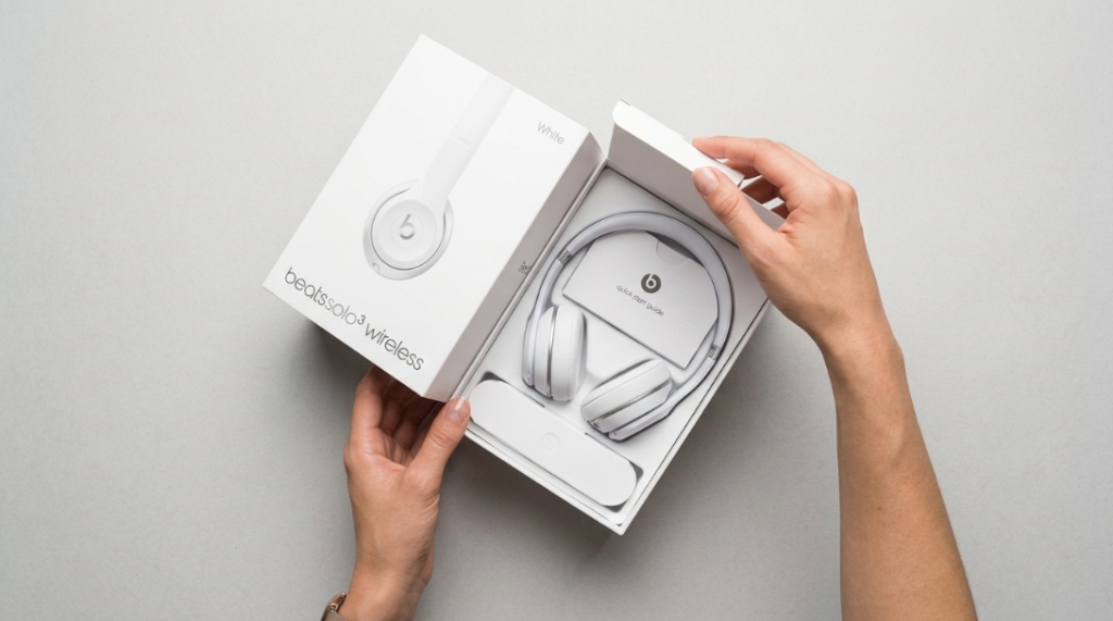 Hands opening an authentic Beats headphones product box for a genuine unboxing experience.