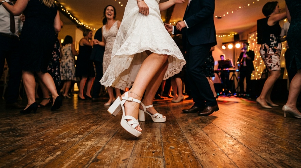 Woman dancing at wedding reception wearing comfortable white platform sandals.