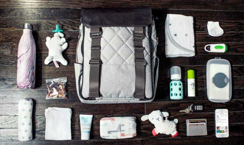Parent organizing diapers, bottles, and wipes in a travel diaper bag