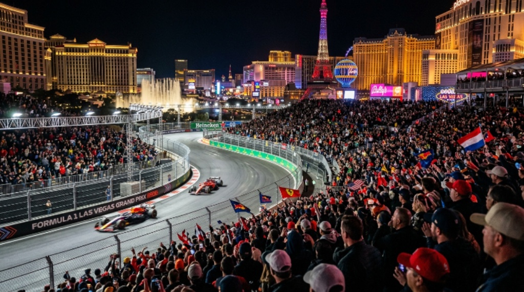 Thousands of race fans in the grandstands watching Formula 1 cars speed past iconic Las Vegas casinos and hotels under neon lights at the 2026 Las Vegas Grand Prix
